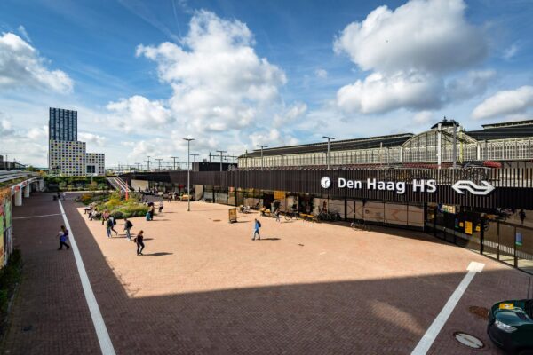 Het Johanna Westerdijkplein met zicht op station Den Haag Hollands Spoor en een kleurrijk hooggebouw op de achtergrond.